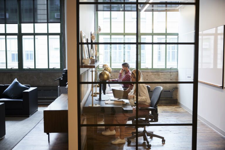 Business team working in a glass walled office booth